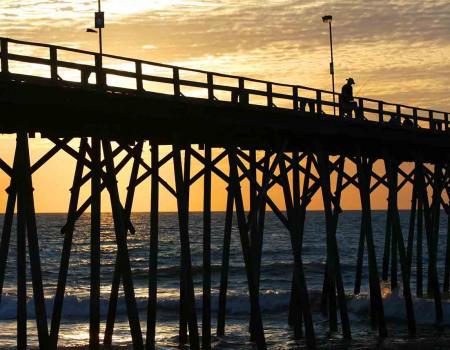 Man fishing from the pier at Kure beach at sunset