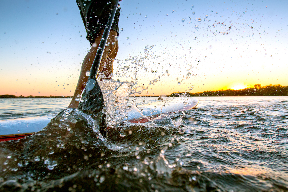 person on a paddleboard close up on the paddle and water